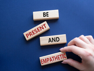 Be Present and Empathetic symbol. Concept words Be Present and Empathetic on wooden blocks. Businessman hand. Beautiful deep blue background. Business concept. Copy space