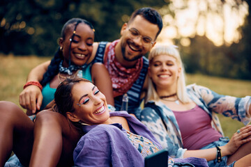 Group of happy festival goers have fun while taking selfie with cell phone.