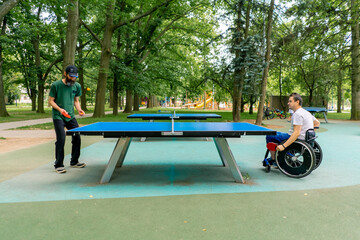 Inclusiveness A disabled man in a wheelchair plays ping pong against an old man with a gray beard...
