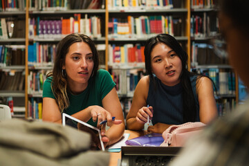 College students studying at the university library. They are preparing an exam.