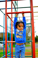 Fototapeta premium beautiful young black African boy with dreadlocks playing in a park .