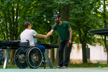 An inclusive disabled man with a racquet in his hand shakes hands with an older man before a game...