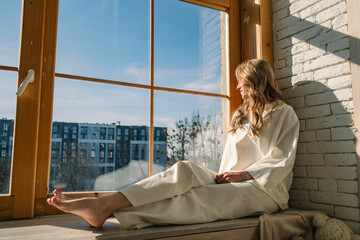 beautiful woman near window highlighted with bright sun