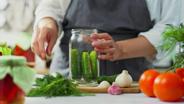An active housewife is engaged in canning vegetables in her home kitchen. The process of pickling vegetables, a white woman of European appearance prepares preparations of vegetables in a marinade