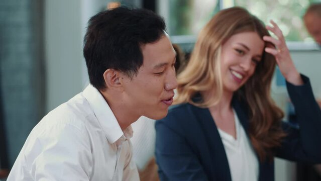 Lifestyle portrait of male marketing intern smiling and talking during relaxed office meeting