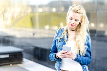 happy blonde young woman outdoor using her mobile phone isolated