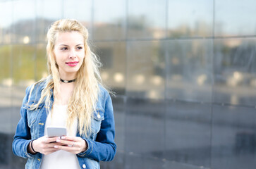 happy blonde young woman outdoor using her mobile phone isolated