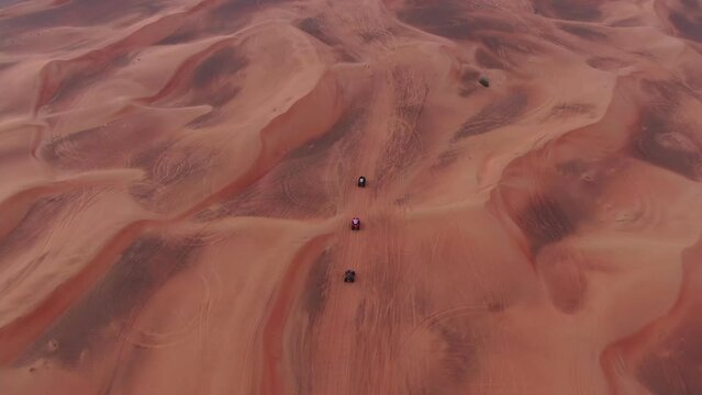 A drone flies over quad bikes driving through the sand dunes of the desert in the United Arab Emirates
