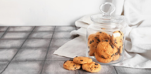 Jar with tasty cookies on grey tile table. Banner for design