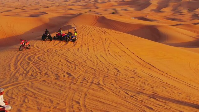 The drone flies to the quadra in cycles standing on sand dunes in the desert of the United Arab Emirates