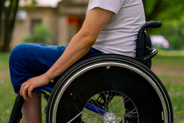Inclusiveness A young man with disabilities rides in a wheelchair in a city park against a...
