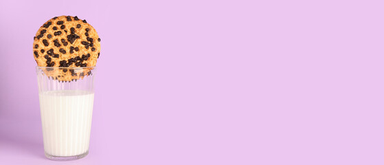 Glass of milk with tasty cookie on lilac background with space for text