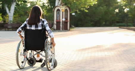 Young woman in wheelchair outdoors, back view