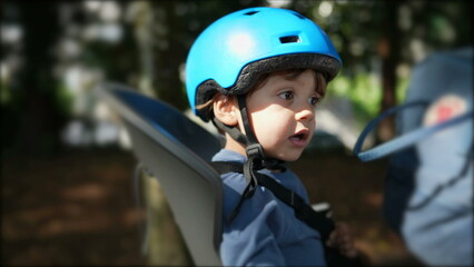 Fototapeta na wymiar Child wearing helmet in bicycle back seat riding bike with parent
