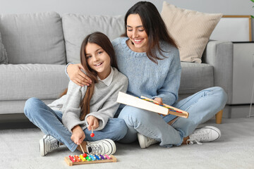 Little girl and her mother in knitted sweaters with toys at home