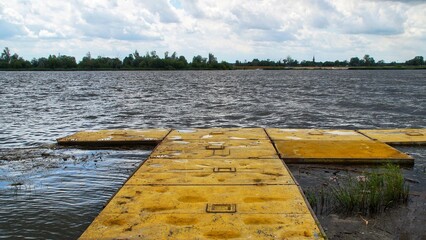 Yellow, floating pier on the Vistula river in Płock during windy weather.
