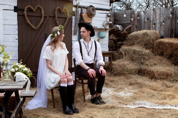 country bride in a white short dress and groom in a white shirt in the village wedding, boho style.