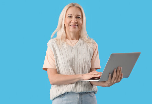 Mature female programmer working with laptop on blue background