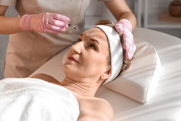 Obraz na płótnie Canvas Mature woman receiving filler injection in beauty salon, closeup