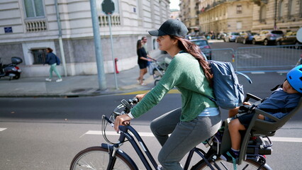 Naklejka na ściany i meble Cyclist mother riding bike with child