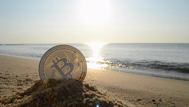 Bitcoin BTC coin in the sand on the sandy beach of the sea coast on a sunny morning close-up. Concept bitcoin money cryptocurrency finance cryptocurrencies crypto bit coin digital web 3.0 cryptography