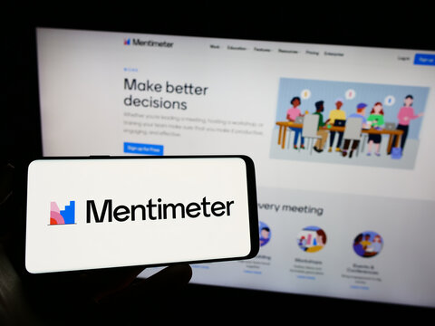 Stuttgart, Germany - 07-09-2023: Person holding cellphone with logo of presentation software company Mentimeter on screen in front of business webpage. Focus on phone display.