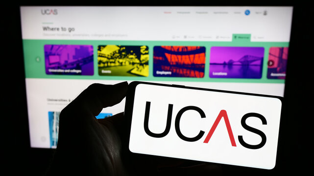 Stuttgart, Germany - 07-09-2023: Person holding mobile phone with logo of Universities and Colleges Admissions Service (UCAS) on screen in front of webpage. Focus on phone display.