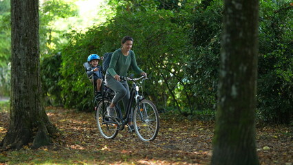 Fototapeta na wymiar Mother riding bicycle with child in bike back seat outside in nature