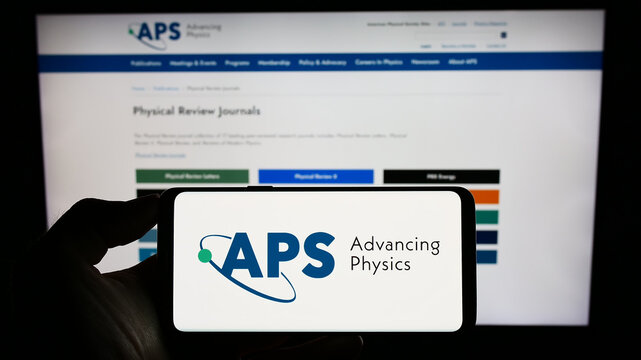 Stuttgart, Germany - 07-09-2023: Person holding cellphone with logo of US organization American Physical Society (APS) on screen in front of webpage. Focus on phone display.