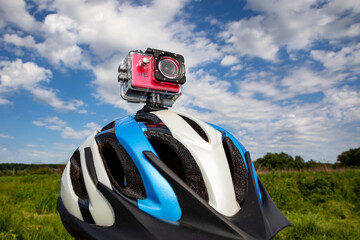 Action camera on a bicycle helmet against a blue sky background.