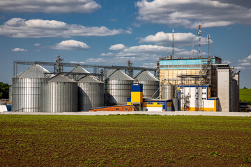 Agricultural Silos. Storage and drying of grains, wheat, corn, soy, sunflower against the blue sky with white clouds.Storage of the crop.