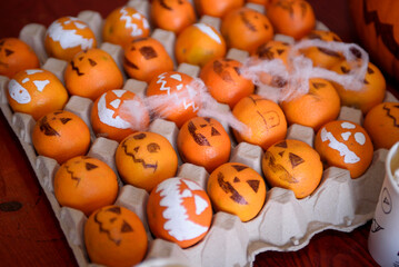Halloween table decoration. Tangerines are decorated in the form of a scary pumpkin. Halloween food for kids.