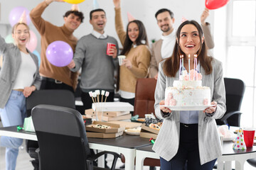 Young woman with Birthday cake making wish at party in office