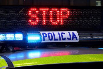 Radiowóz polska policja z Sygnalizator błyskowy niebieski na dachu radiowozu. Alarmowo wieczorem