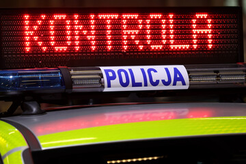 Radiowóz polska policja z Sygnalizator błyskowy niebieski na dachu radiowozu. Alarmowo wieczorem - obrazy, fototapety, plakaty