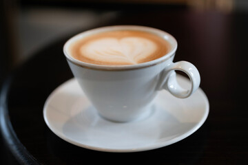 Cappuccino in white cup on saucer with latte art on top