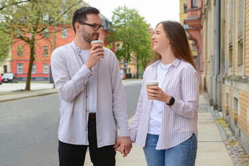 Beautiful loving happy couple drinking coffee and walking in city on spring day