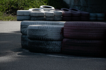 Small tire runoff on a sports track. Tires of different sizes and colors, some of them damaged. The...