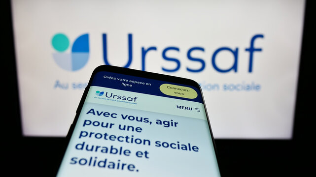 Stuttgart, Germany - 07-12-2023: Mobile phone with website of French social security organization URSSAF on screen in front of business logo. Focus on top-left of phone display.