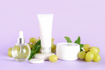 Composition with cosmetic products, spa stones and grapes on color background