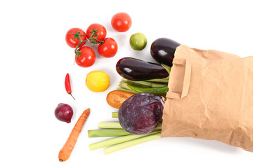 Paper bag full of fresh vegetables and baguette on white background