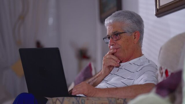 Concerned senior man in front of laptop computer with preoccupied frustrated expression. Gray-hair elderly person feeling stress and anxiety about negative outcomes while using technology