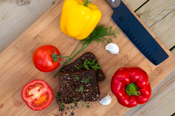 two slices of rye fresh bread on a wooden board served with paprika, garlic cloves, dill and rosemary, healthy food concept
