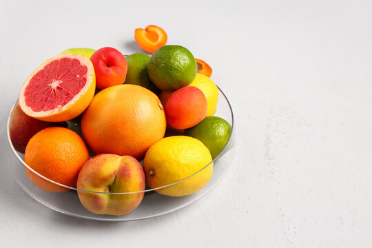 Bowl with different fresh fruits on grey background © Pixel-Shot