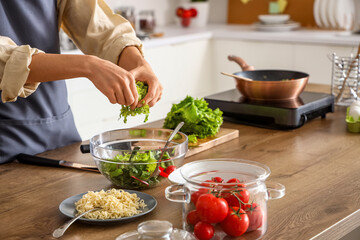 Young Asian man making vegetable salad in kitchen