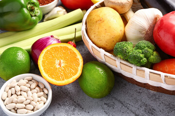Wicker bowl with different fresh vegetables and cereals on blue background, closeup
