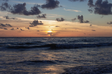 lever de soleil derrière les nuages au dessus de l'océan avec des vagues tel que vu à partir de...