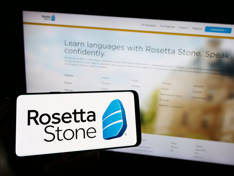 Stuttgart, Germany - 07-12-2023: Person holding cellphone with logo of US education technology company Rosetta Stone Inc. on screen in front of webpage. Focus on phone display.