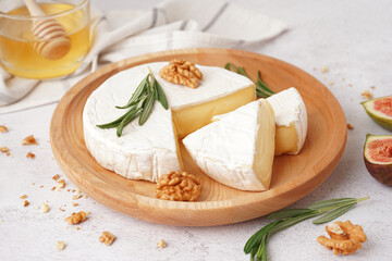 Plate with pieces of tasty Camembert cheese on light background