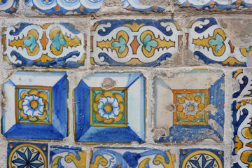 Old damaged tiles with floral ornate painted in Spain. Real textured multi coloured ceramic background. Vivid colours remains. Vintage architectural details